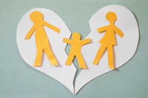A paper doll family of two parents and a child over the top of a ripped paper heart, representing Divorce in Washington IL