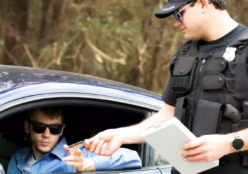 Police officer checking a license and issuing speeding tickets