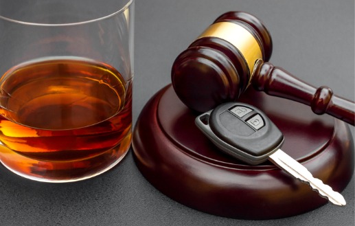 A gavel with a car key and next to a glass of alcohol, representing DUI Defense in Peoria IL